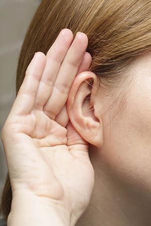 A woman with a hand cupped around her ear