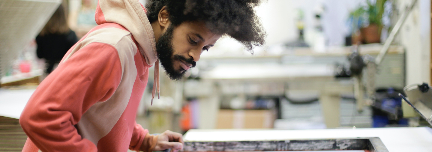 Man with afro screen printing on a table