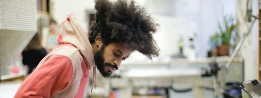 Man with afro in studio focused on his work 